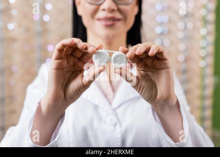 vista parziale dell'oculista sfocato che mostra il case dell'obiettivo nel salone dell'ottica Foto Stock