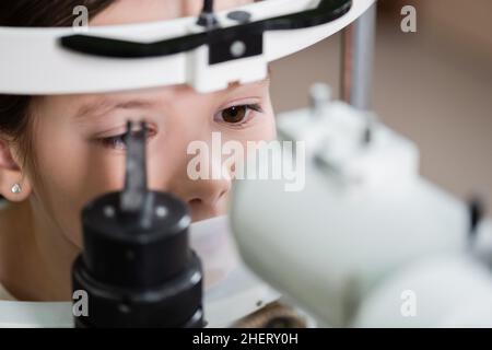 misurazione della vista da parte del bambino su un autorefrattore sfocato Foto Stock