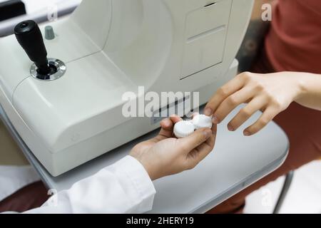 vista parziale dell'optometro che fornisce la custodia della lente al paziente vicino all'autorefrattore Foto Stock