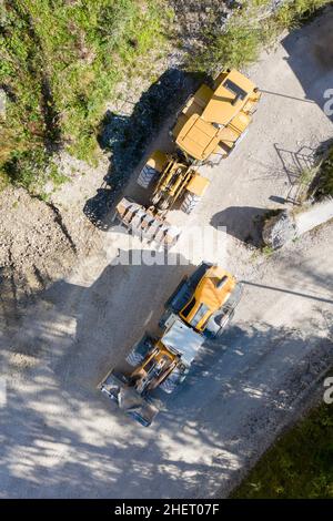 vista dall'alto di due caricatori frontali montati su ruote arancioni in cava di pietra Foto Stock