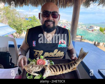 Erick Higuera o Pelon de Hospicio con un pesce curvina, branzino fritto in un ristorante di pesce e frutti di mare sulla spiaggia di Kino Bay, sonora. (Foto di Luis Gutierrez / NortePhoto) Erick Higuera o Pelon de Hospicio con un pescado curvina, corvina frita en restaurante de pescados y mariscos en la baia di playa Kino, sonora. (Foto di Luis Gutierrez / NortePhoto) Foto Stock