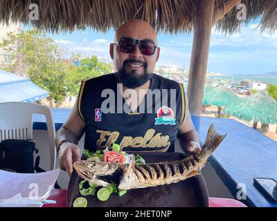 Erick Higuera o Pelon de Hospicio con un pesce curvina, branzino fritto in un ristorante di pesce e frutti di mare sulla spiaggia di Kino Bay, sonora. (Foto di Luis Gutierrez / NortePhoto) Erick Higuera o Pelon de Hospicio con un pescado curvina, corvina frita en restaurante de pescados y mariscos en la baia di playa Kino, sonora. (Foto di Luis Gutierrez / NortePhoto) Foto Stock