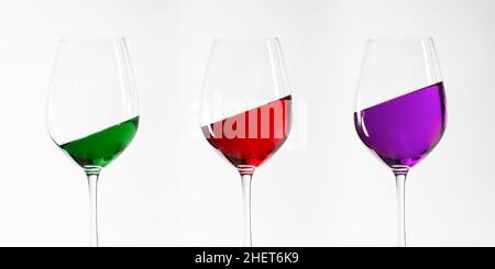 tre bicchieri da vino verdi rossi e porpora inclinati Foto Stock
