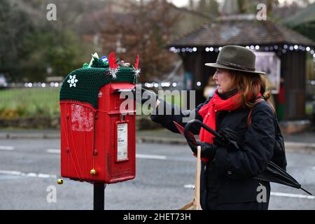 Ultimo post per le carte di Natale donna che postano le carte una casella di posta decorata Xmas in Coalbrookdale, Shropshire, ukl Foto Stock