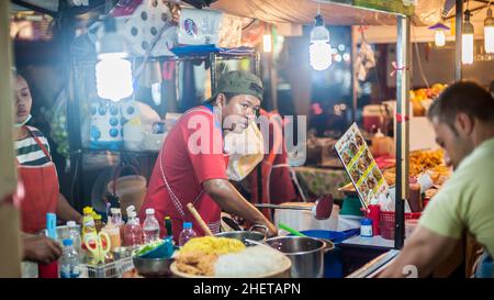 PHUKET, TAILANDIA - 10. MARZO 2018. Un venditore asiatico non identificato prepara il cibo per strada. Pad Thai. Foto editoriale del giorno Foto Stock