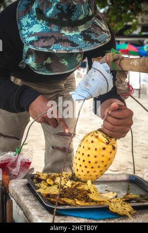 KOH SAMUI, TAILANDIA - 22. MAGGIO 2018. Uomo locale che vende frutta fresca su una spiaggia. Molta verdura e frutta ingredienti importanti della tradizione thailandese Foto Stock