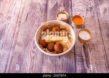 Ciotola con crocchette rotonde, yucca fritta e salse da bagnare Foto Stock