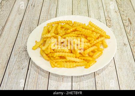 Le patatine fritte vengono preparate tagliandole a fette o bastoncini e friggerle in olio caldo fino a quando non diventano dorate, togliendole dall'olio e poi dal mare Foto Stock