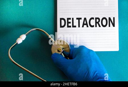 Nuovo simbolo di deformazione variante del deltacron codice-19. Mano nel guanto blu con nota bianca. Parola di concetto Deltacron. Stetoscopio. Medico e COVID-19 deltacron Foto Stock