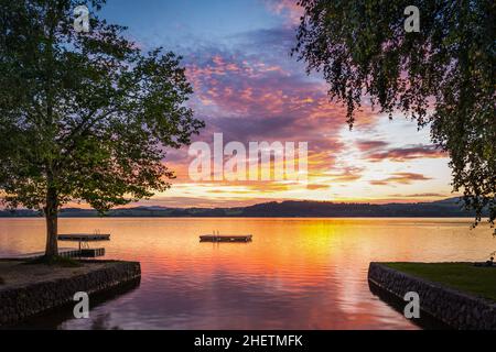 moody tramonto al lago wallersee in austria con alberi e piattaforma in legno Foto Stock