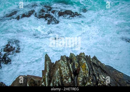 Onde selvatiche che colpiscono sulle grandi rocce della costa Foto Stock