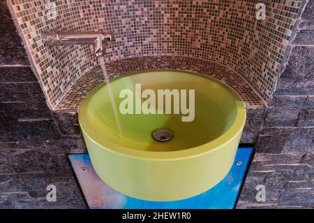 ciotola verde con rubinetto d'acqua nichelato con tessere di mosaico e acqua corrente Foto Stock