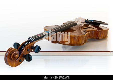 violino classico in legno adagiato sul suo bastone con sfondo bianco Foto Stock