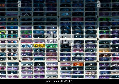 molti occhiali da sole colorati e sfumature in scatole bianche Foto Stock