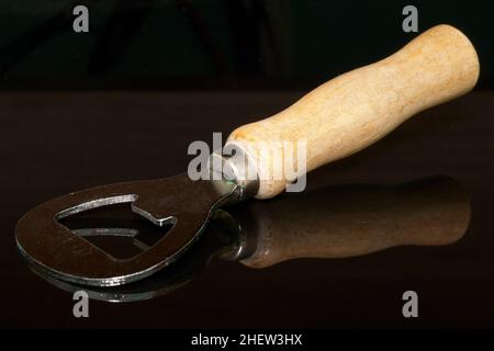 apribottiglie in legno e metallo su sfondo nero Foto Stock