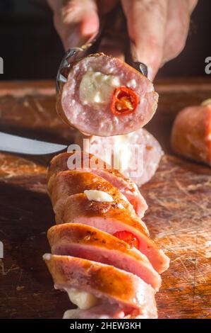 Salsiccia e peperoni, salsiccia artigianale con formaggio e pepe su un asse di legno, spazio copia e fuoco selettivo Foto Stock