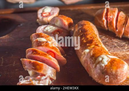 Salsiccia e peperoni, salsiccia artigianale con formaggio e pepe su un asse di legno, spazio copia e fuoco selettivo Foto Stock