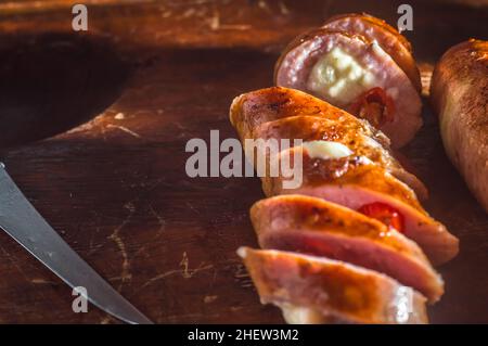 Salsiccia e peperoni, salsiccia artigianale con formaggio e pepe su un asse di legno, spazio copia e fuoco selettivo Foto Stock