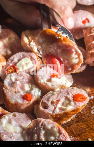 Salsiccia e peperoni, salsiccia artigianale con formaggio e pepe su un asse di legno, spazio copia e fuoco selettivo Foto Stock