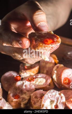 Salsiccia e peperoni, salsiccia artigianale con formaggio e pepe su un asse di legno, spazio copia e fuoco selettivo Foto Stock