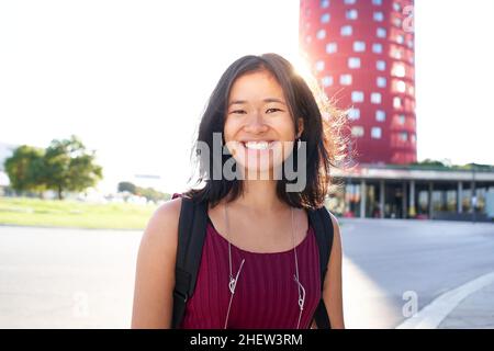 Ritratto di una bella giovane donna a Barcellona. Lei è asiatica, nei primi anni '20, bruna con capelli lunghi. Guardando la fotocamera e sorridendo. Intelligente Foto Stock