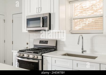 Cucina moderna bianca Condo con elettrodomestici in acciaio inox e armadi in stile Shaker Foto Stock