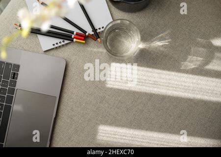 Primo piano, vista dall'alto di un'area di lavoro accogliente e luminosa con computer portatile, cancelleria, arredamento e spazio per fotocopie sul tavolo Foto Stock