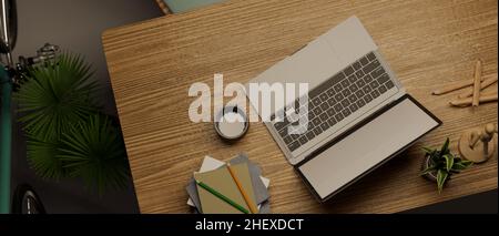 Vista dall'alto di un comodo spazio di lavoro con computer portatile aperto su un tavolo di legno. 3d rendering, illustrazione 3d Foto Stock