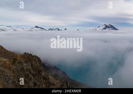 Bella vista del Lago Garibaldi da Panorama Ridge escursione in British Columbia, Canada. Montagne e ghiacciai che sbucano attraverso le nuvole nel backgr Foto Stock