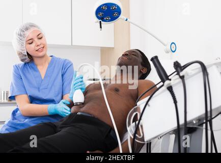 Afro uomo americano che ha cavitazione procedura in clinica di bellezza Foto Stock