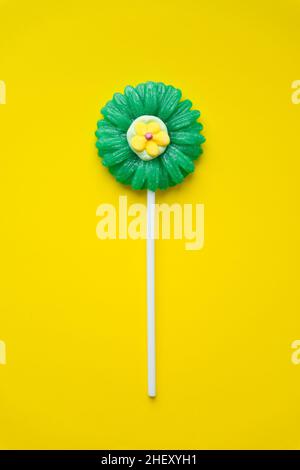 Lollipop a forma di fiore su sfondo giallo. Vista dall'alto delle caramelle Lollipop. Foto Stock