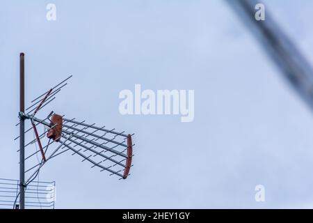 antenna televisiva in piedi sul tetto sotto il cielo blu chiaro Foto Stock