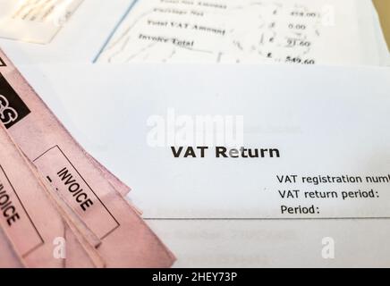 Primo piano di un documento di imposta sul valore aggiunto britannico con fatture su una scrivania. Foto Stock