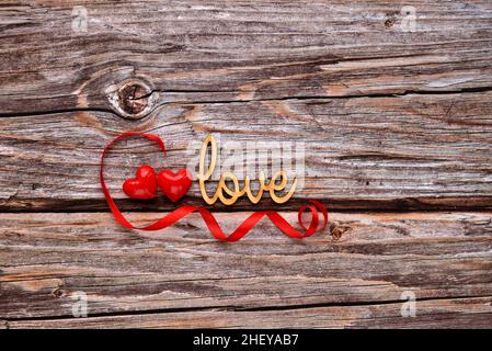 La parola 'Amore' con i cuori su vecchio sfondo di legno per i vostri saluti per un giorno di San Valentino Foto Stock