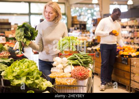 Donna acquistare verdure nel supermercato Foto Stock