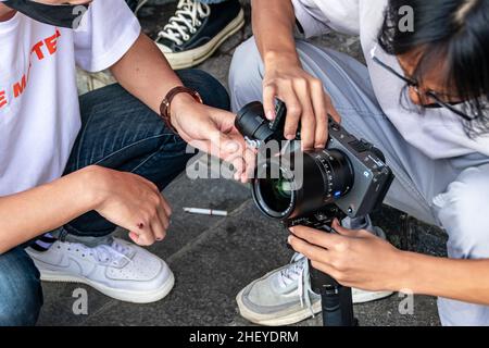 un giovane fotografo che lavora in squadra per impostare la fotocamera e gimbal per il loro lavoro sul marciapiede Foto Stock