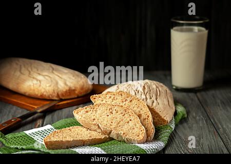 Pane fatto in casa appena sfornato con un bicchiere di latte sul tavolo Foto Stock