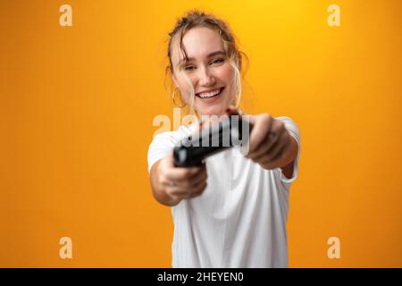 La giovane donna gioca con il joystick su sfondo giallo Foto Stock