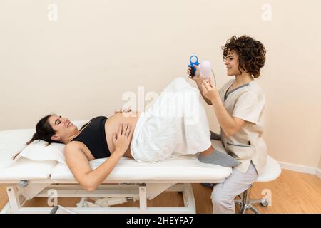 Ginecologo in possesso di un apparato muscolo pelvico del pavimento esercizio per preparare per la nascita di una donna sdraiata Foto Stock