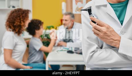 Audiologo con otoscopio su medico di consulenza di base con paziente bambino e sua madre in clinica uditiva. Trattamento dell'orecchio e esame dell'udito Foto Stock