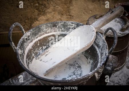 Cucchiaio di legno pieno di farina presso il vecchio bakehouse. Processo di fabbricazione in epoca medievale Foto Stock