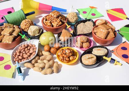 Carta da parati Makar sankranti con piatti speciali del festival Sankranti serviti e consumati come Peanut chikki, tilgul laddu, til baati, frutta bor, arachidi, Foto Stock