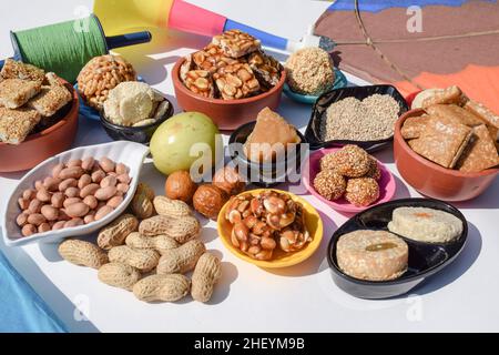 Carta da parati Makar sankranti con piatti speciali del festival Sankranti serviti e consumati come Peanut chikki, tilgul laddu, til baati, frutta bor, arachidi, Foto Stock