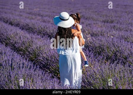 Madre e figlia che camminano nel campo della lavanda in una bella giornata estiva Foto Stock