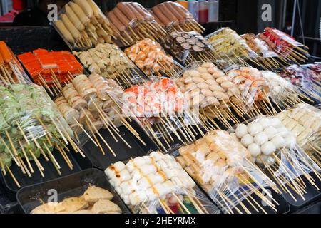 Vari tipi di snack o cibi a base di carne lavorati, come salsicce, carne di manzo cornuta, tempura colorata, sono venduti sulla strada nella zona di Malioboro. Foto Stock