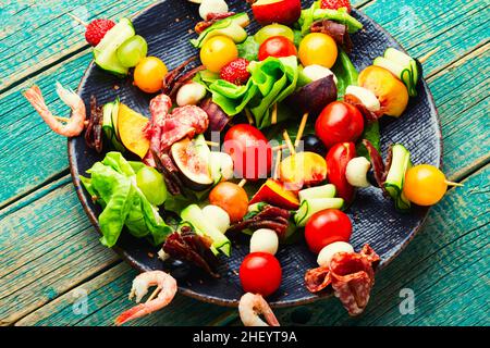 Spuntino festivo di gamberetti, jamon, frutta e verdure su spiedini di legno. Foto Stock