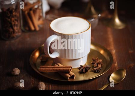 Tazza di spezia di zucca tardiva o di eggnog con bastoncini di cannella, anice stellato di zucche e noce moscata in un ambiente rustico e vintage Foto Stock