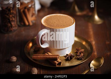 Tazza di spezia di zucca tardiva o di eggnog con bastoncini di cannella, anice stellato di zucche e noce moscata in un ambiente rustico e vintage Foto Stock