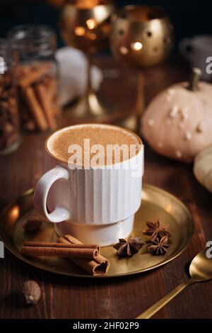 Tazza di spezia di zucca tardiva o di eggnog con bastoncini di cannella, anice stellato di zucche e noce moscata in un ambiente rustico e vintage Foto Stock