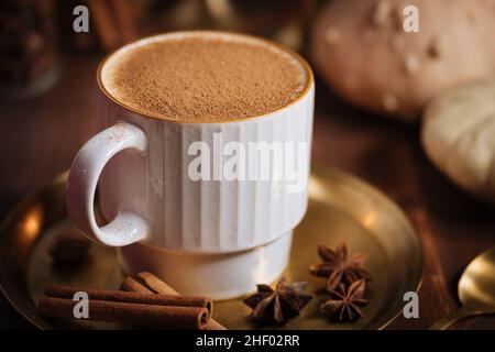 Tazza di spezia di zucca tardiva o di eggnog con bastoncini di cannella, anice stellato di zucche e noce moscata in un ambiente rustico e vintage Foto Stock